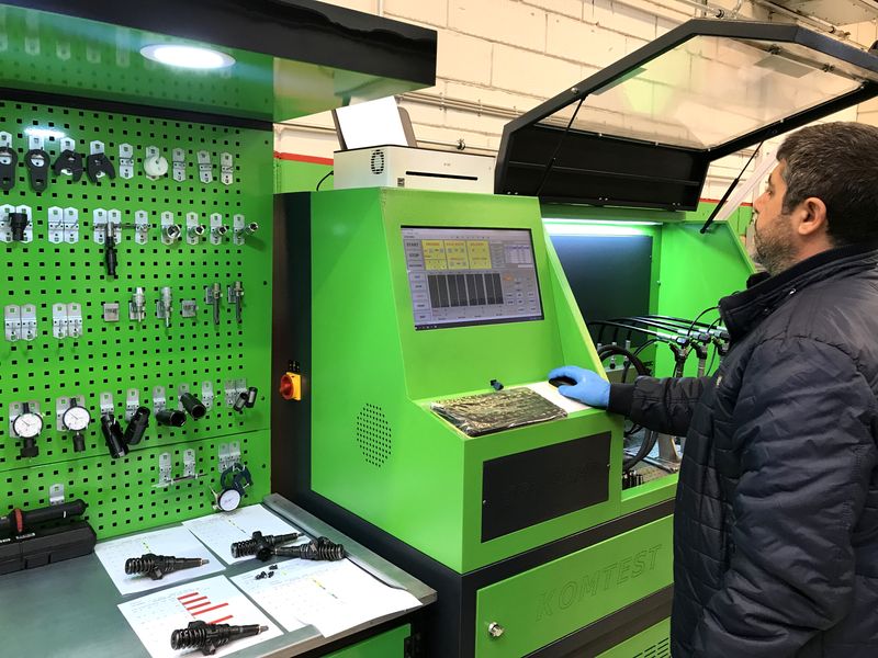 Tekniker aflæser måledata på testbænken hos Diesel Clinic med udskrevne testrapporter på bordet